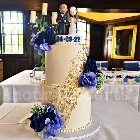 Two-tier custom cake with blue florals and gold leaf