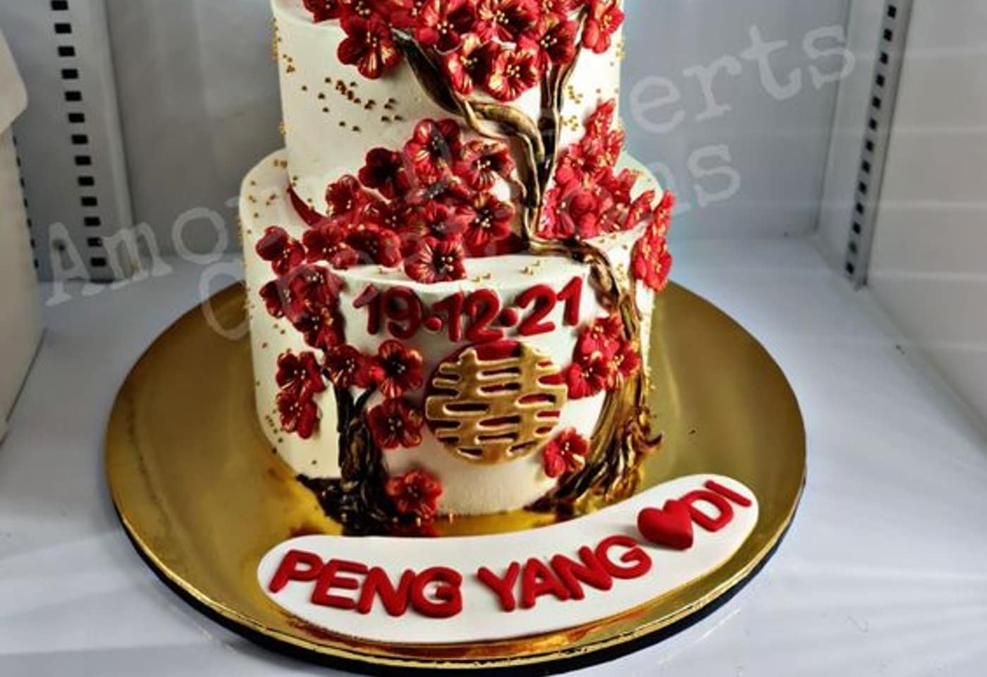 Red blossom branches, gold double happiness symbol, and the wedding date piped on a Chinese custom cake by Amour Desserts