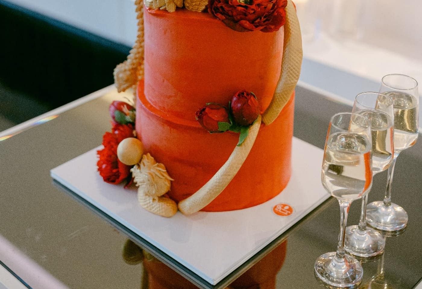 Two-tier red custom cake with sculpted gold dragon and phoenix detail, set up at a Melbourne reception